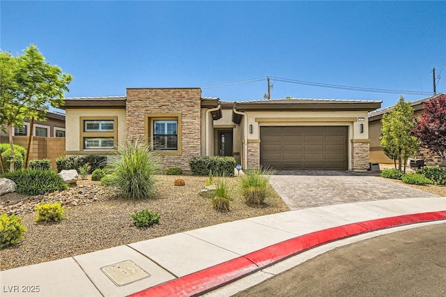 view of front of property featuring an attached garage, decorative driveway, stucco siding, and stone siding
