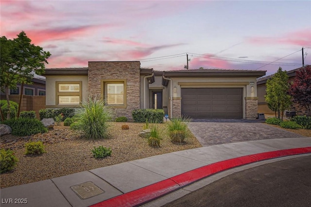 view of front facade featuring stucco siding, driveway, and stone siding