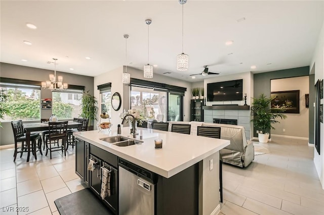 kitchen featuring stainless steel dishwasher, a sink, a healthy amount of sunlight, and a fireplace