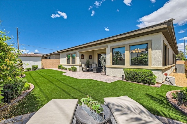 back of house with a lawn, fence, stucco siding, and a patio area