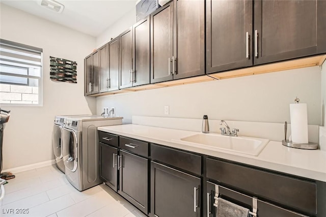 laundry area with light tile patterned flooring, baseboards, washer and clothes dryer, a sink, and cabinet space
