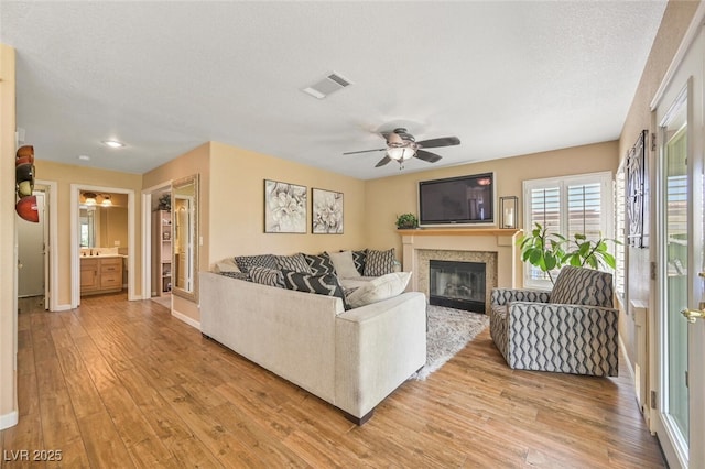 3295 Cooper Creek Dr, Henderson, NV 89074 - living room featuring light wood-type flooring, visible vents, ceiling fan, and a glass covered fireplace