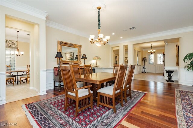 dining room featuring visible vents, wood finished floors, an inviting chandelier, and ornamental molding
