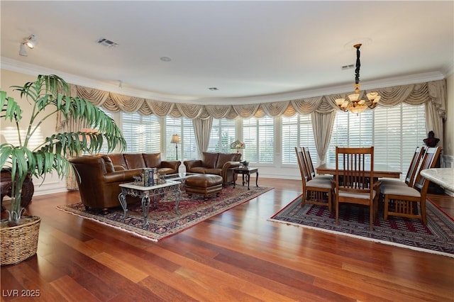 dining space with crown molding, an inviting chandelier, a wealth of natural light, and wood finished floors