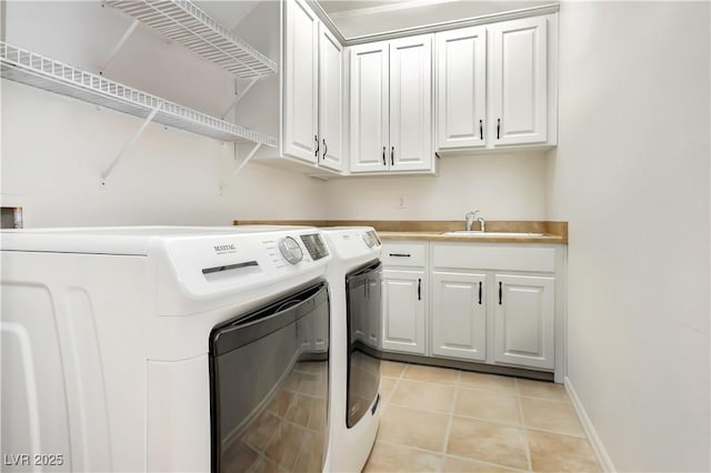 laundry room featuring a sink, cabinet space, washer and clothes dryer, light tile patterned flooring, and baseboards