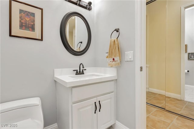 bathroom featuring toilet, tile patterned flooring, vanity, and baseboards