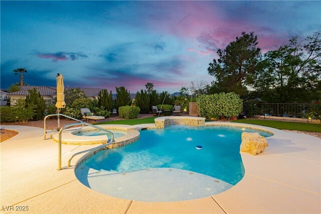 pool at dusk featuring fence, a pool with connected hot tub, and a patio area