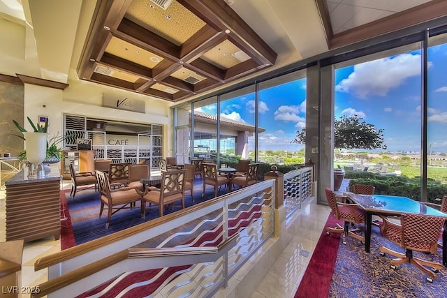 interior space featuring a wall of windows, tile patterned flooring, coffered ceiling, and a healthy amount of sunlight