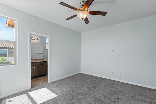 unfurnished bedroom featuring carpet, baseboards, ensuite bath, and ceiling fan