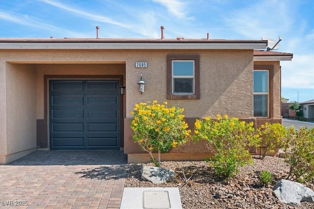 view of front of house featuring stucco siding, an attached garage, and driveway