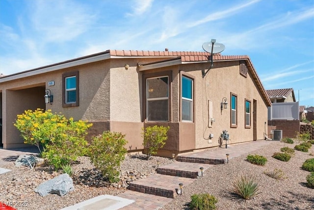 view of home's exterior with central AC, stucco siding, and a patio area