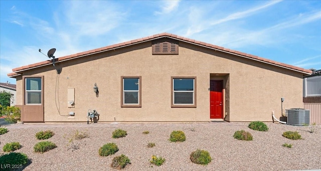 back of house with central AC unit and stucco siding