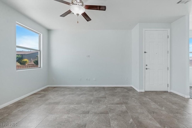empty room with baseboards, a ceiling fan, and stone finish flooring