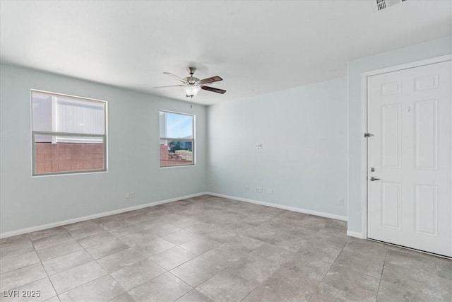 empty room with ceiling fan, baseboards, and light tile patterned floors