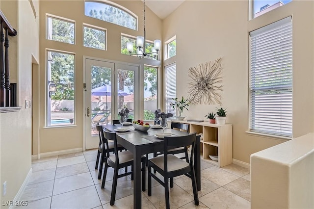 dining area featuring baseboards, a chandelier, light tile patterned floors, and a high ceiling