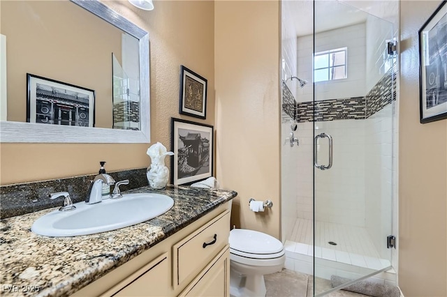 bathroom with a shower stall, toilet, and vanity
