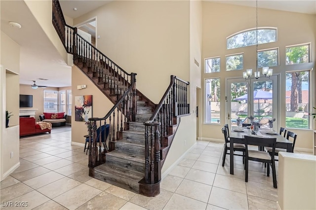stairway featuring a chandelier, plenty of natural light, a towering ceiling, tile patterned flooring, and baseboards