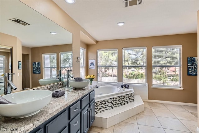 bathroom featuring a bath, double vanity, baseboards, and recessed lighting