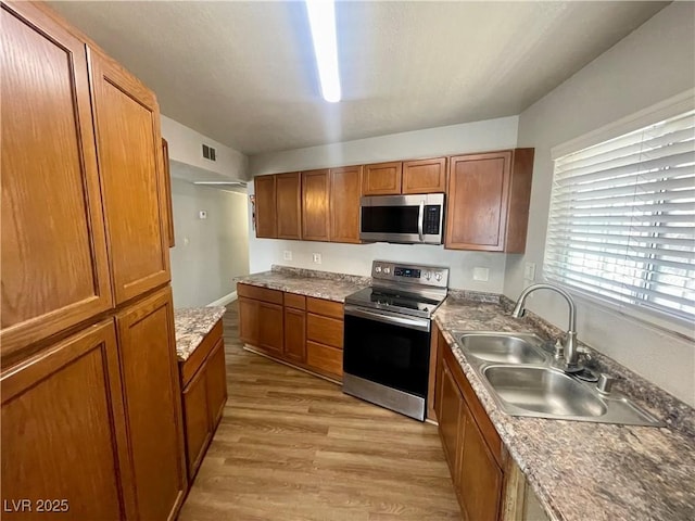 4682 Tamalpias Ave, Las Vegas, NV 89120 - kitchen featuring stainless steel appliances, brown cabinetry, and light wood finished floors