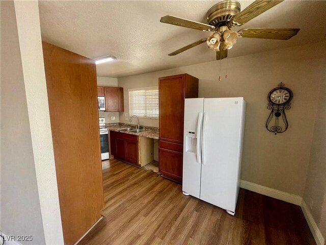 4682 Tamalpias Ave, Las Vegas, NV 89120 - kitchen with appliances with stainless steel finishes, light wood finished floors, ceiling fan, and light stone countertops