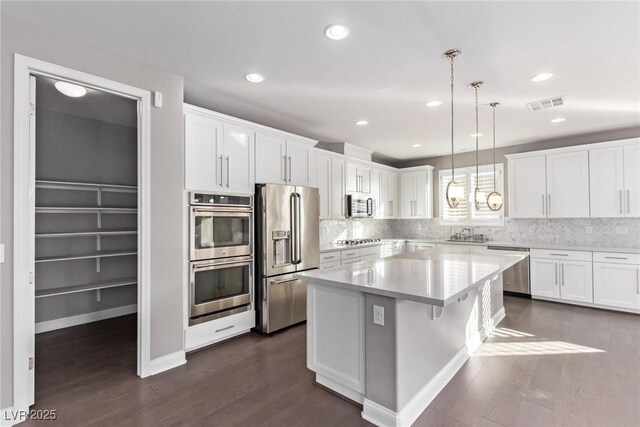 8797 Pinley Spring St, Las Vegas, NV 89113 - kitchen with stainless steel appliances, white cabinets, dark wood-style flooring, light countertops, and recessed lighting