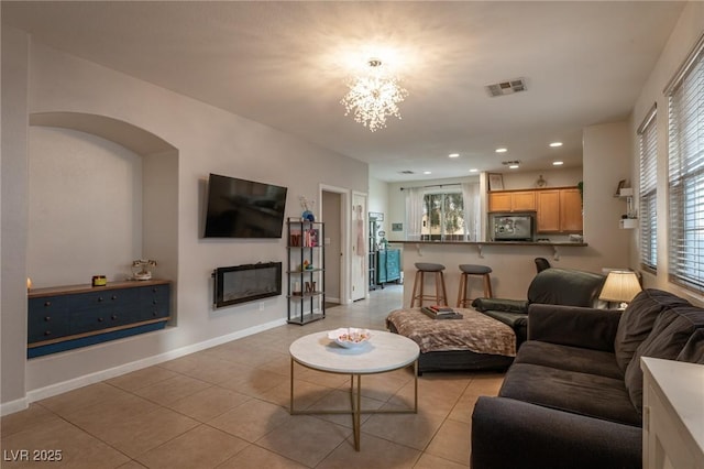 living room with a chandelier, visible vents, a healthy amount of sunlight, and light tile patterned floors