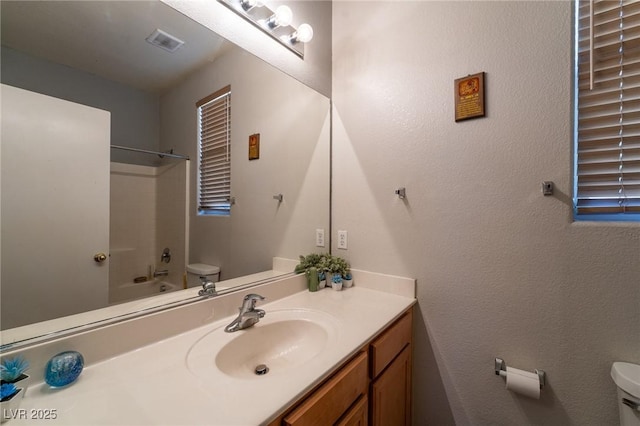 bathroom with visible vents, washtub / shower combination, toilet, and vanity