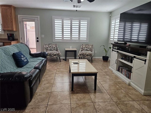 living area featuring light tile patterned flooring, a ceiling fan, visible vents, and baseboards