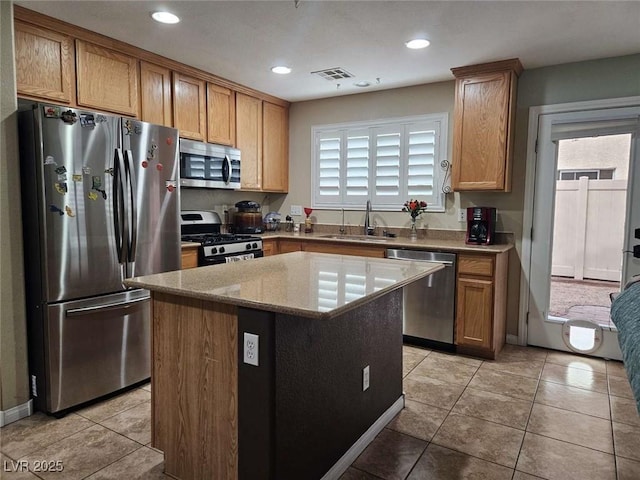 kitchen with light tile patterned floors, a sink, visible vents, stainless steel appliances, and a kitchen island