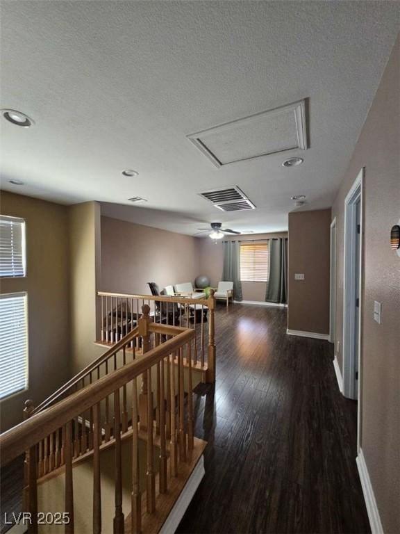 hall featuring an upstairs landing, wood finished floors, visible vents, and baseboards