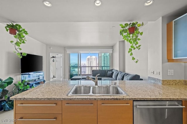 kitchen with light stone counters, stainless steel dishwasher, a sink, open floor plan, and recessed lighting