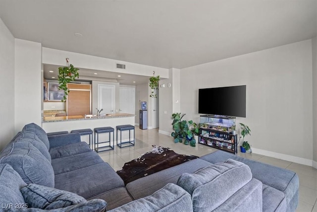 living area with light tile patterned flooring, visible vents, and baseboards