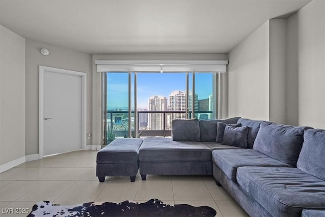 living area featuring light tile patterned flooring, a city view, and baseboards