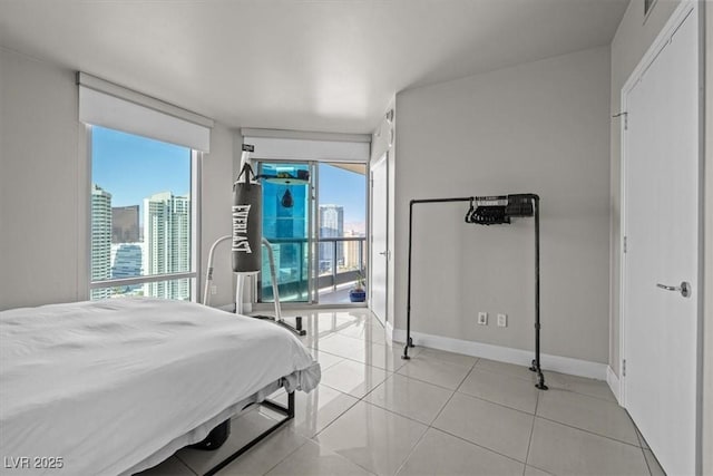 bedroom featuring light tile patterned floors, a view of city, access to outside, and baseboards