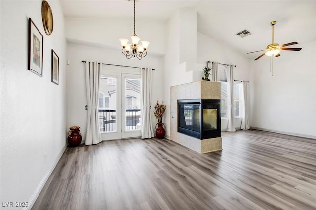 unfurnished living room featuring wood finished floors, a tiled fireplace, plenty of natural light, and visible vents