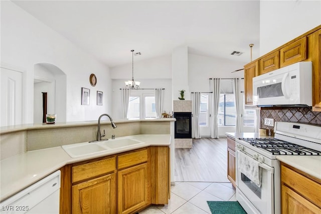 kitchen featuring a sink, decorative backsplash, vaulted ceiling, white appliances, and plenty of natural light