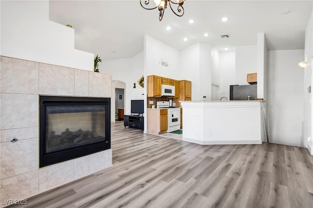 unfurnished living room with visible vents, high vaulted ceiling, light wood-style floors, and a fireplace