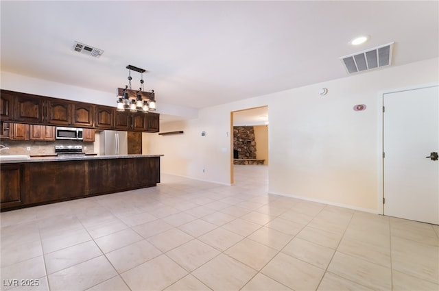 711 Sari Dr, Las Vegas, NV 89110 - kitchen featuring appliances with stainless steel finishes, light countertops, dark brown cabinets, tasteful backsplash, and pendant lighting