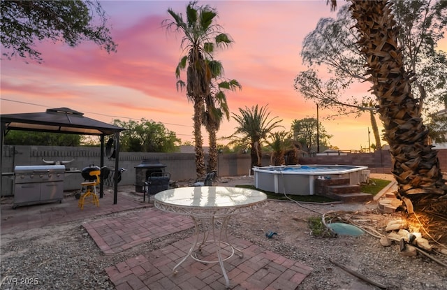 711 Sari Dr, Las Vegas, NV 89110 - patio terrace at dusk with a gazebo, area for grilling, a patio area, and a fenced backyard