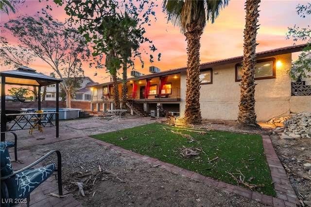 711 Sari Dr, Las Vegas, NV 89110 - back of property at dusk with a gazebo, stairs, a patio area, stucco siding, and a yard