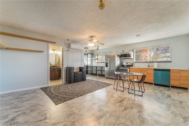 711 Sari Dr, Las Vegas, NV 89110 - kitchen with stainless steel appliances, a wall mounted air conditioner, a textured ceiling, ceiling fan, and light countertops