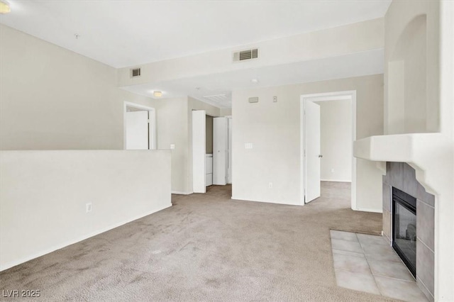 unfurnished living room featuring a tile fireplace, visible vents, and light carpet