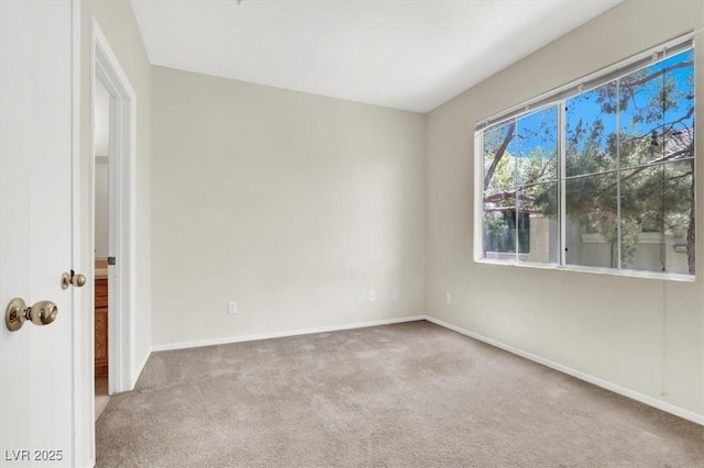 carpeted empty room featuring baseboards