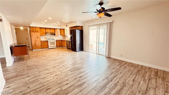 201 Redstone St, Las Vegas, NV 89145 - kitchen featuring brown cabinetry, under cabinet range hood, white range with gas cooktop, baseboards, and black fridge