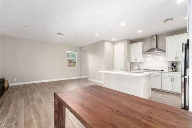 1049 Williamtown Ave, North Las Vegas, NV 89084 - kitchen with open floor plan, light wood-style floors, wall chimney range hood, and gas stovetop