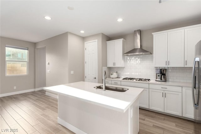 1049 Williamtown Ave, North Las Vegas, NV 89084 - kitchen with tasteful backsplash, light wood-style flooring, stainless steel appliances, wall chimney range hood, and a sink