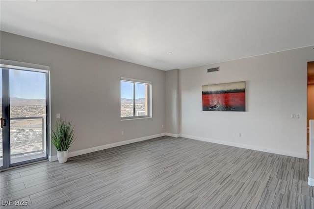 spare room featuring visible vents, wood finished floors, and baseboards
