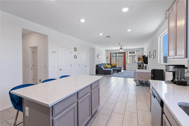 kitchen featuring gray cabinets, recessed lighting, stainless steel dishwasher, a ceiling fan, and a kitchen breakfast bar