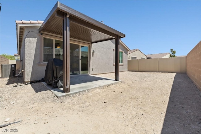rear view of house featuring cooling unit, stucco siding, a fenced backyard, and a patio area