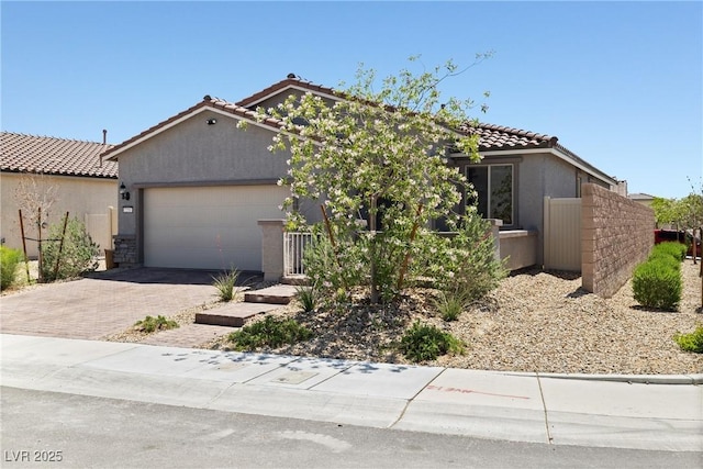 view of front of home featuring stucco siding, fence, decorative driveway, a tile roof, and an attached garage